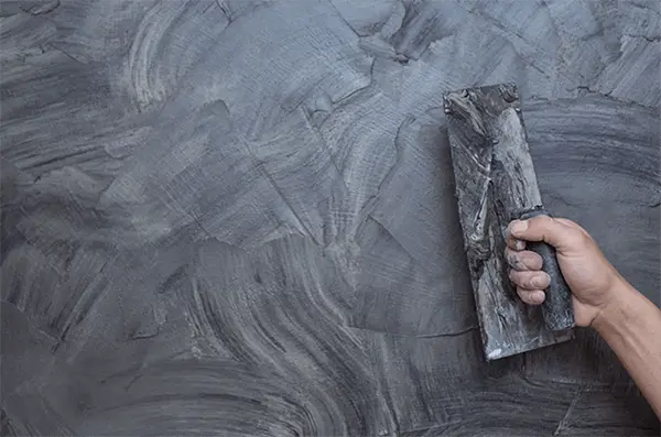 Profissional aplicando cimento queimado para parede e piso, criando acabamento moderno e durável com produtos da Casa da Textura.